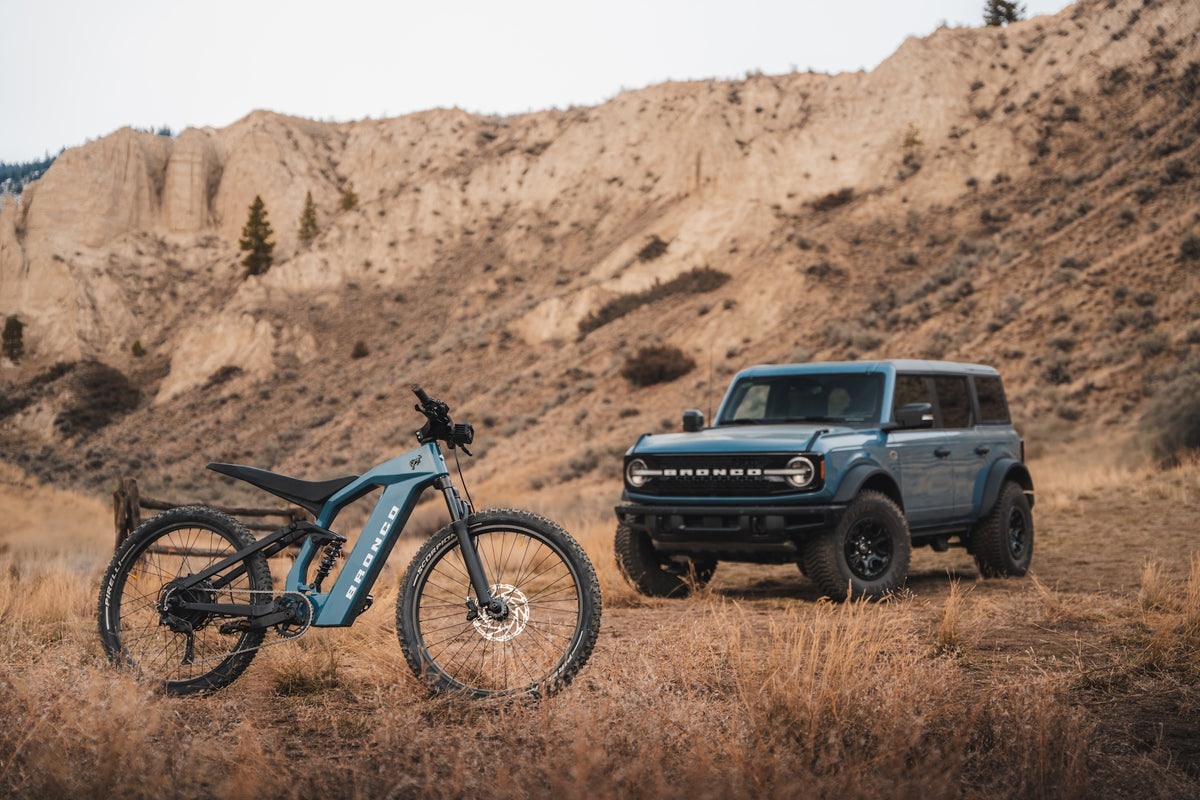 Bronco eBike positioned in front of a Ford Bronco vehicle in an open landscape. Used to illustrate trail-inspired design.